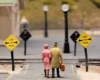 Two figures stand at a railroad crossing on a model railroad layout