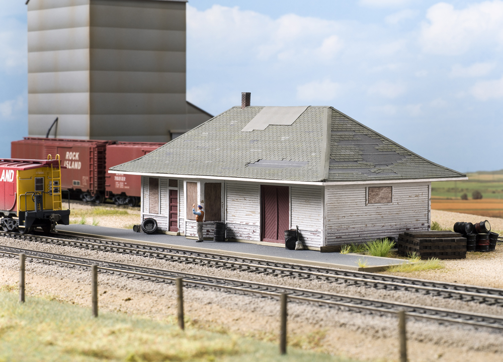 Color photo of train passing abandoned depot.