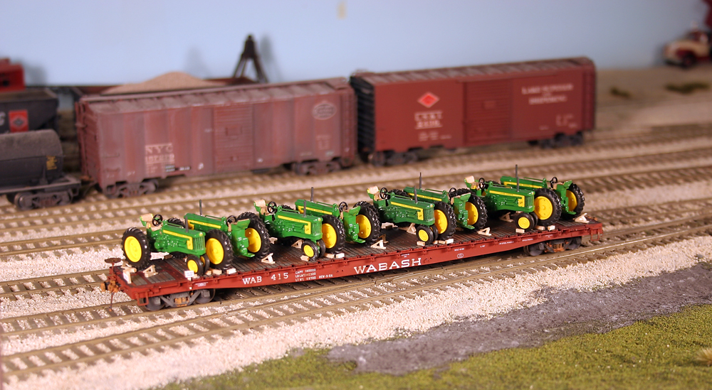 Color photo showing HO scale flatcar with tractor loads.