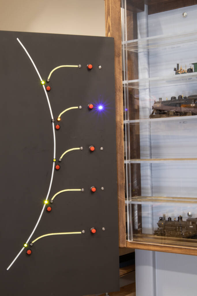 A black board with lines, lights, and buttons next to a display case