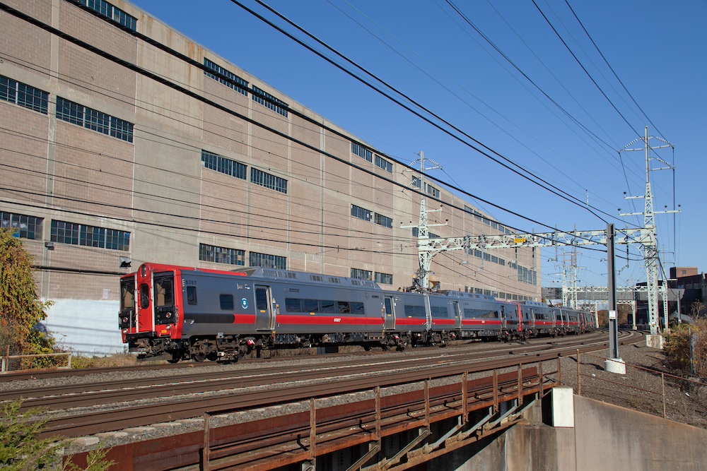 Commuter train passes by building in the background.