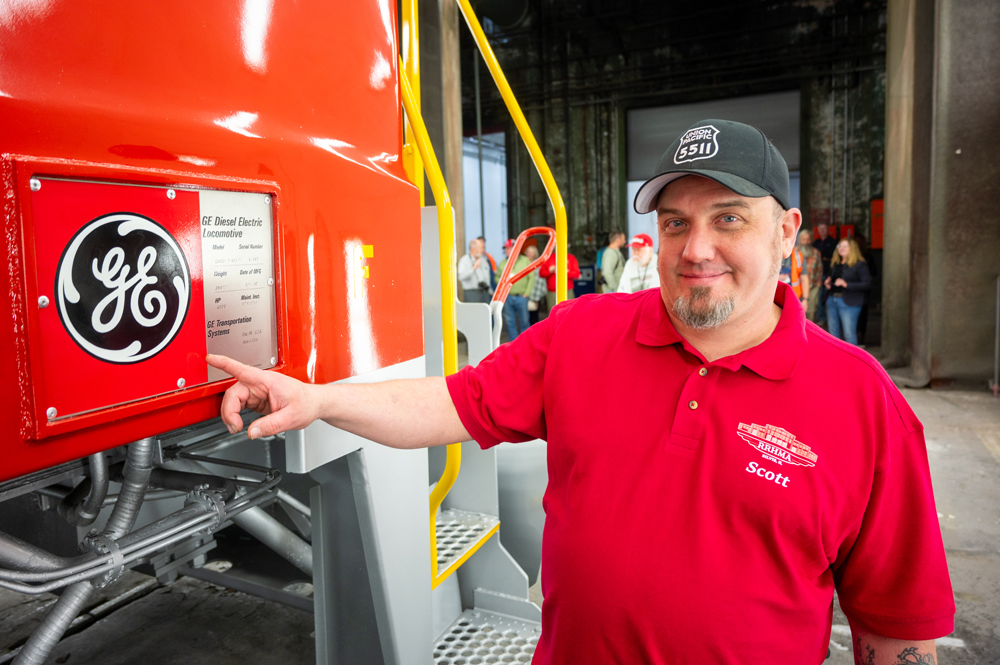 Man pointing at metal plate on locomotive