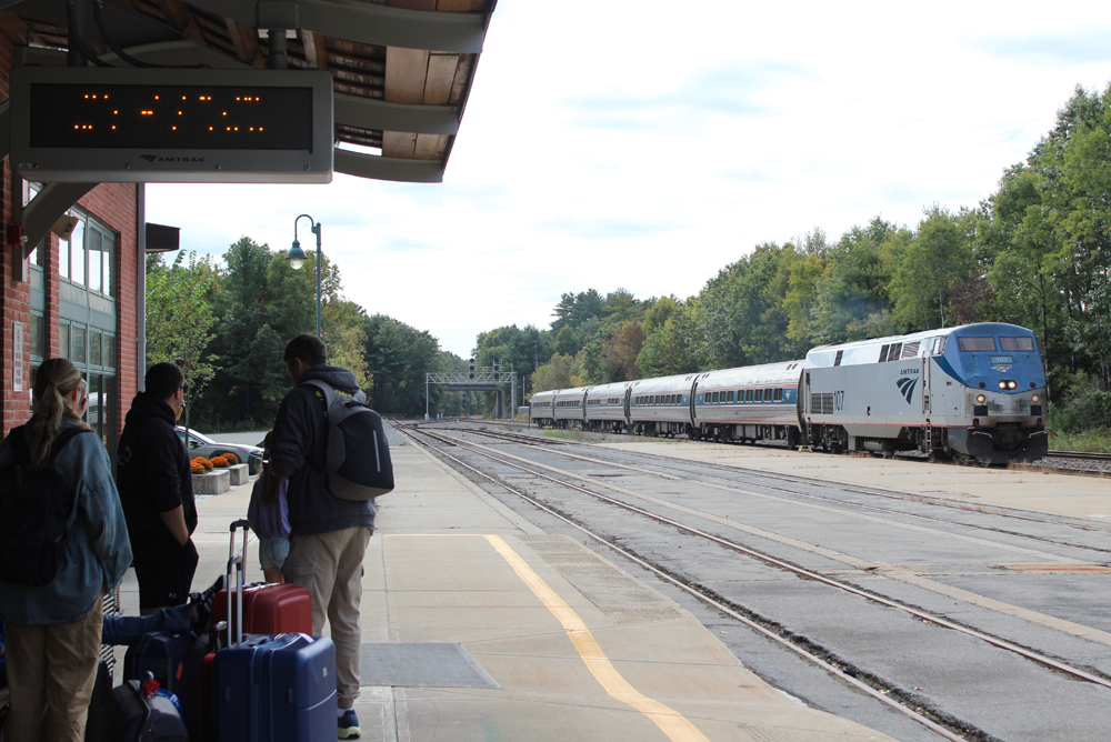 People wait on station platform as passenger train arrives