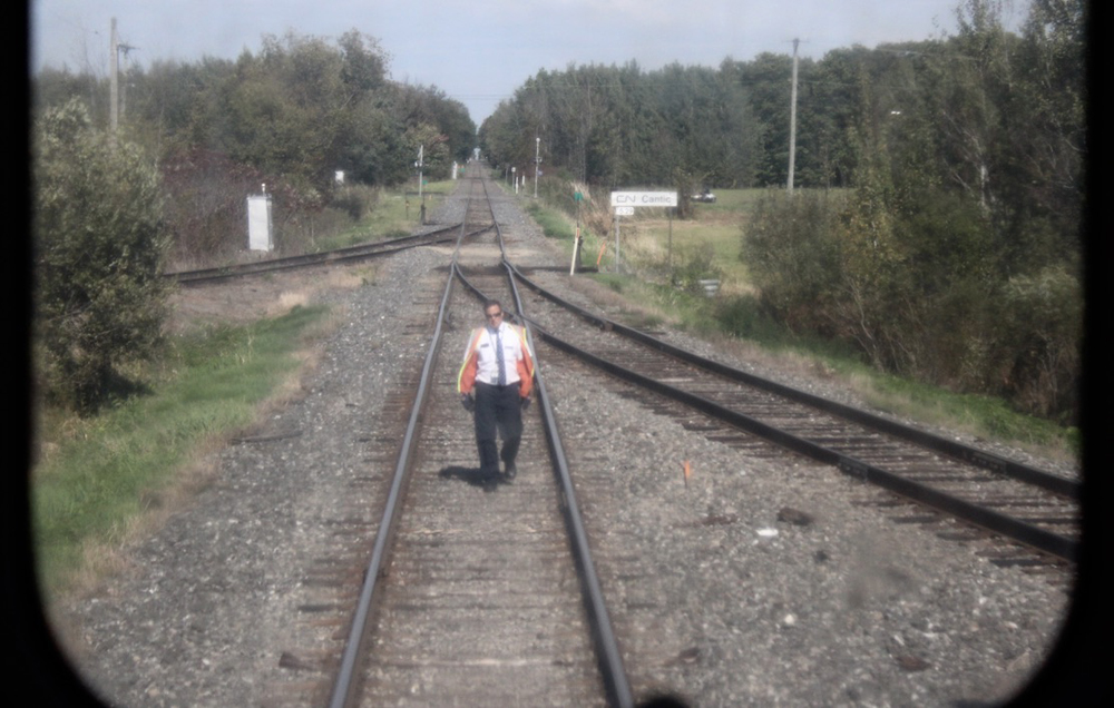 Train crew member walking on tracks behind train