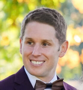 Head shot of man in coat and bow tie