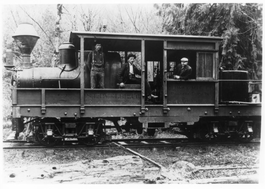 Black-and-white photography of geared steam locomotive with cab enclosing most of engine