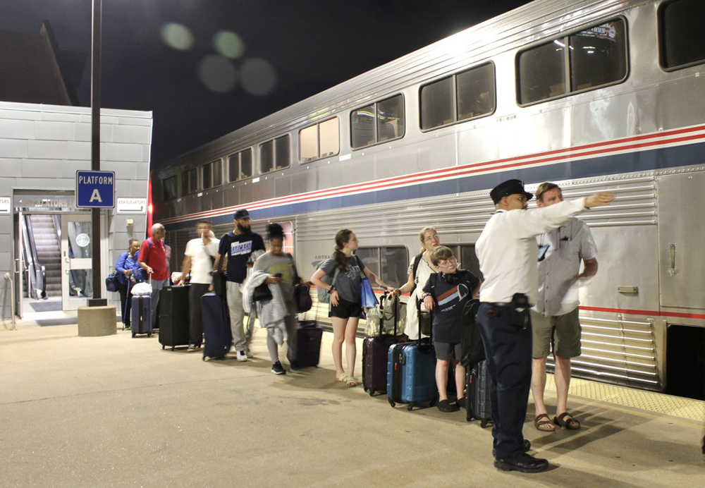 Conductor points while speaking to passenger as train boards at station