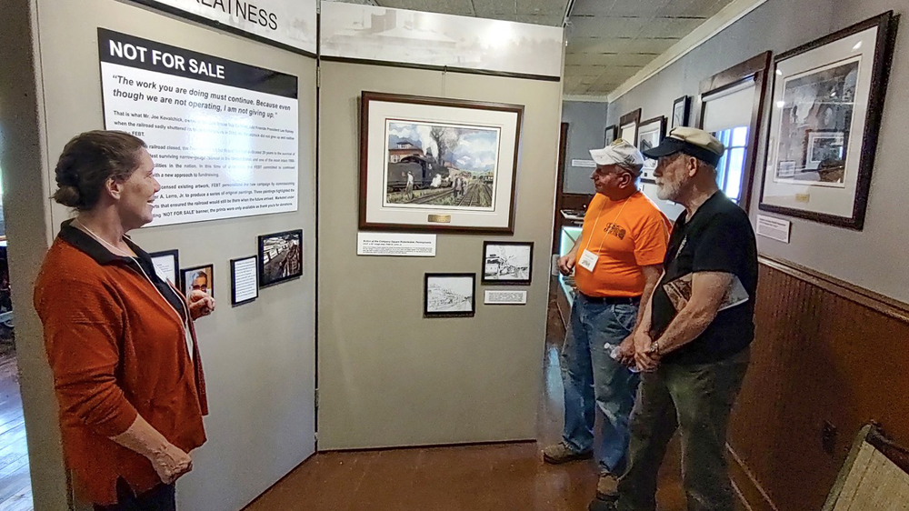 Men looking at painting on display as exhibit curator looks on