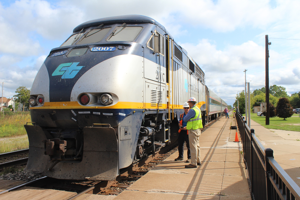 Men standing next to train with locomotive lettered for Caltrain