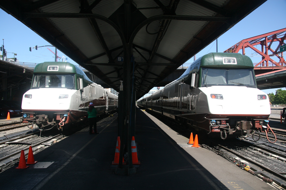 Two cab cars of single-level train on adjacent tracks at station