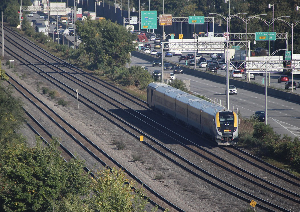 Passenger train on multi-track main line adjacent to highway