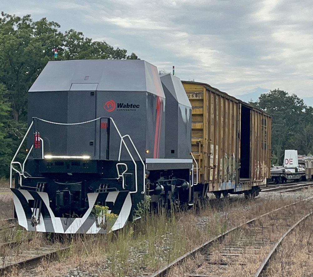 Boxy gray autonomous locomotive prototype with boxcar