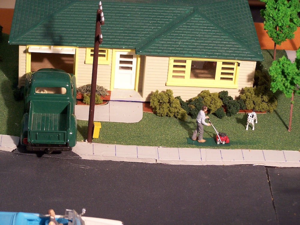 model house with truck and man mowing lawn