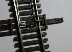 A black plastic N scale switch pinned to a white board