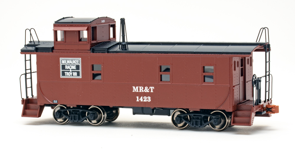 Color photo of HO scale caboose painted brown and black on white background.