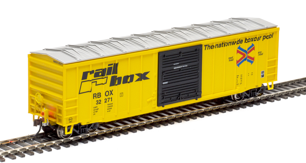 Color photo of yellow boxcar with black door and aluminum roof on section of track.