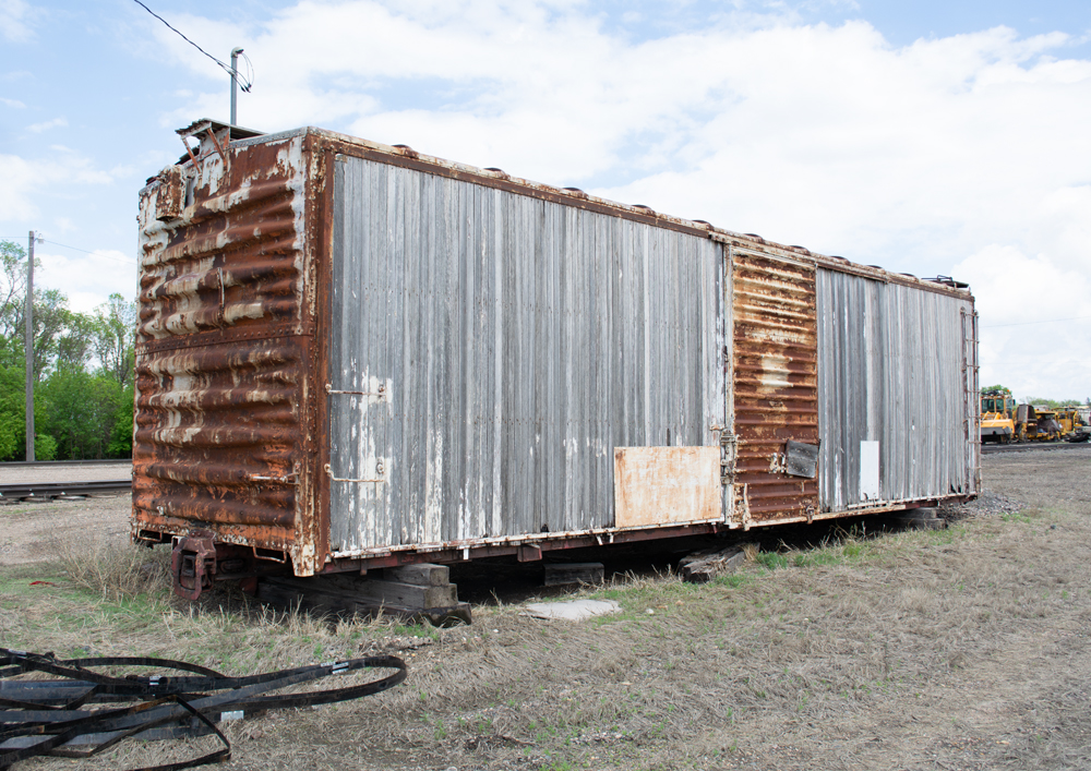 Color photo showing right side of heavily weathered wood and steel boxcar.