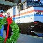 man and woman holding wreath in front of Amtrak train