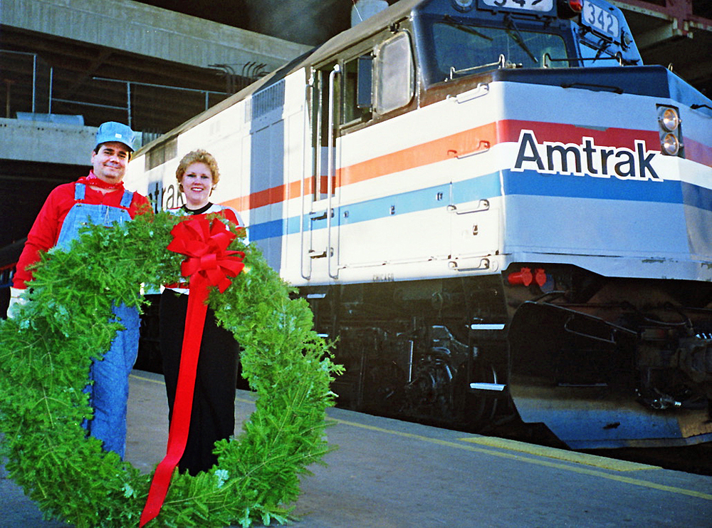 man and woman holding wreath in front of Amtrak train