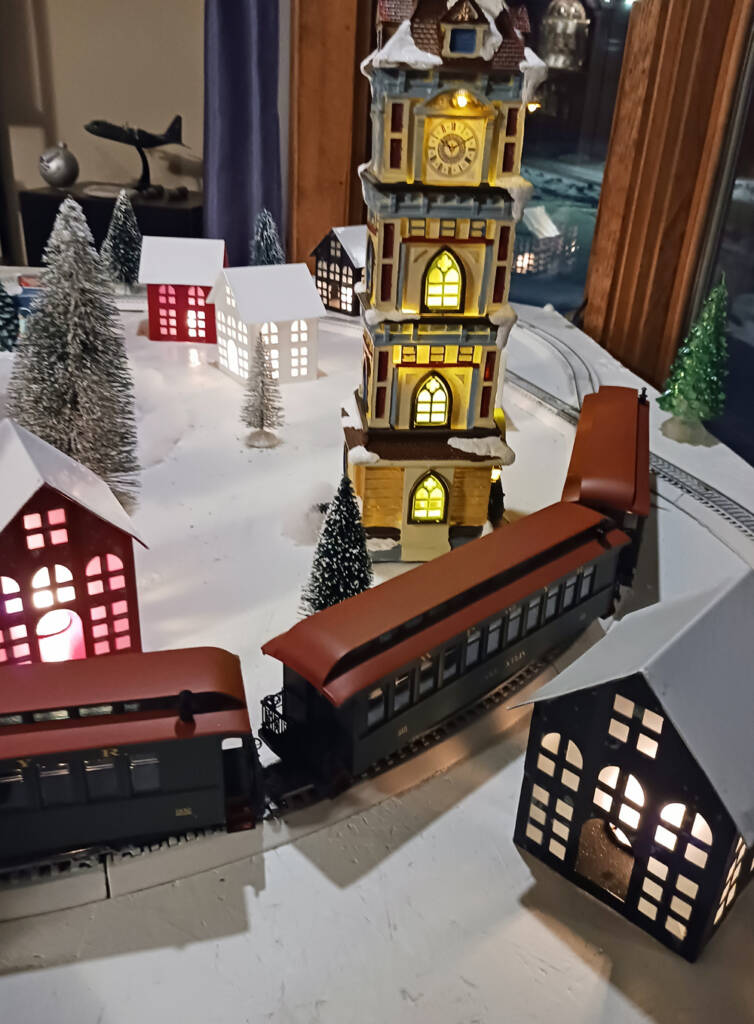 A model train in front of a clocktower