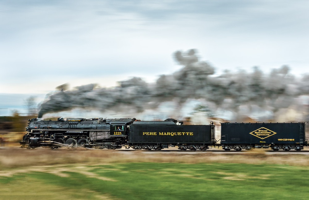 Panning shot of a steam locomotive with Pere Marquette No. 1225 stacking up miles in Fall and Winter operations.