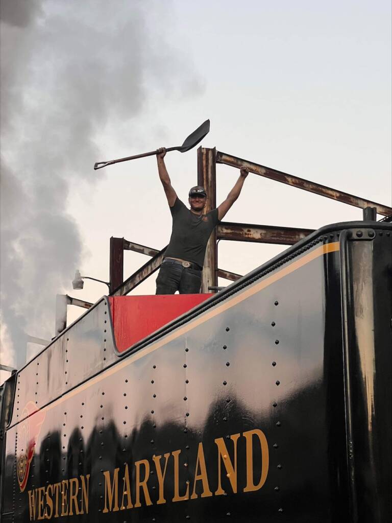 Young individual standing on top of a steam locomotive tender