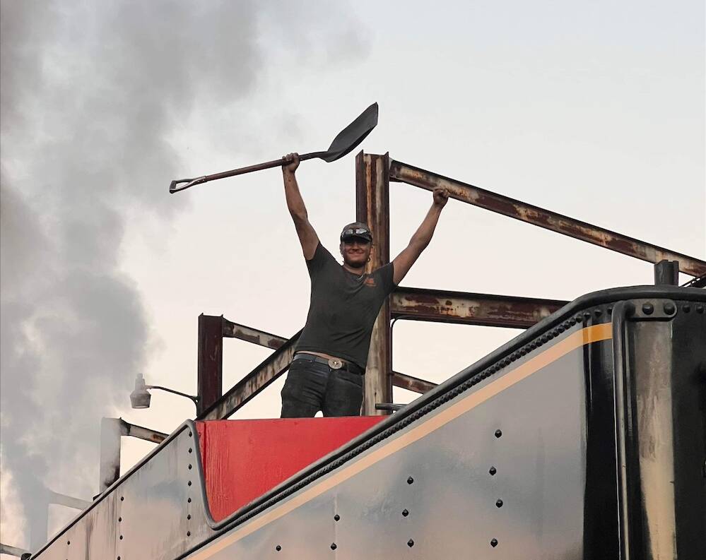 Young individual standing on top of a steam locomotive tender