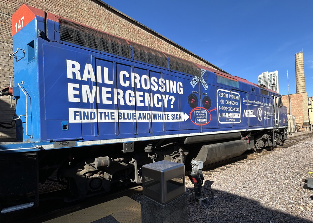 Commuter locomotive with information on blue grade-crossing signs