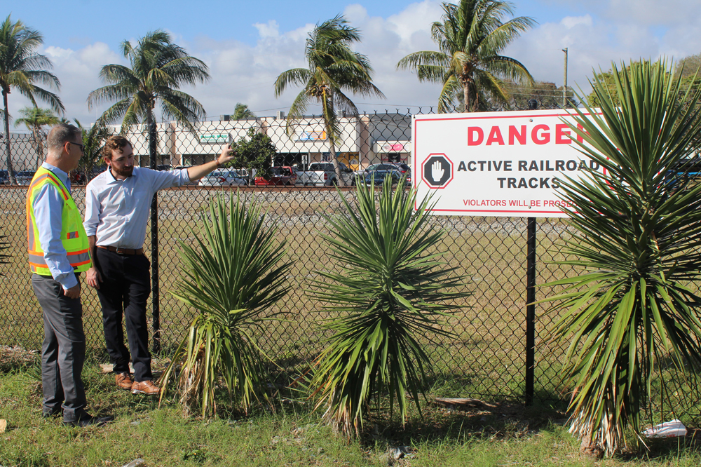 Two men next to fence with warning sign