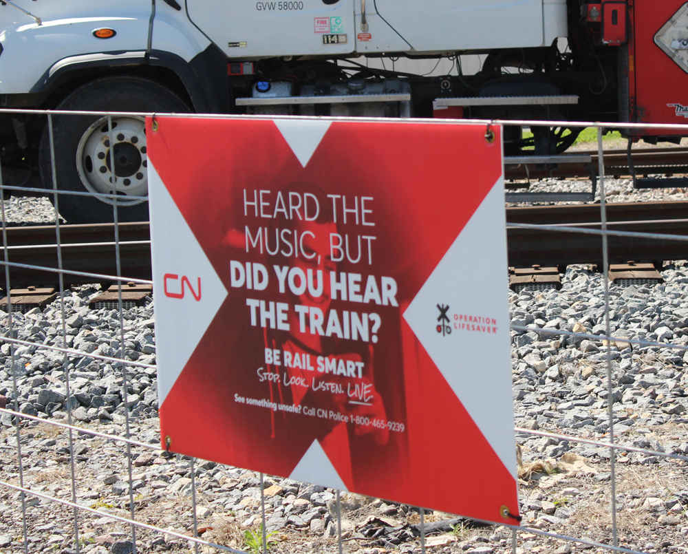 Red-and-white sign for pedestrians to be aware of surroundings at tracks