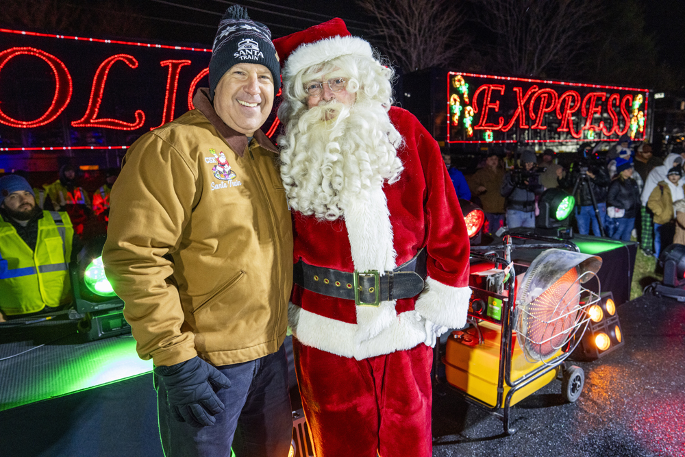 Man in yellow jacket standing with Santa Claus