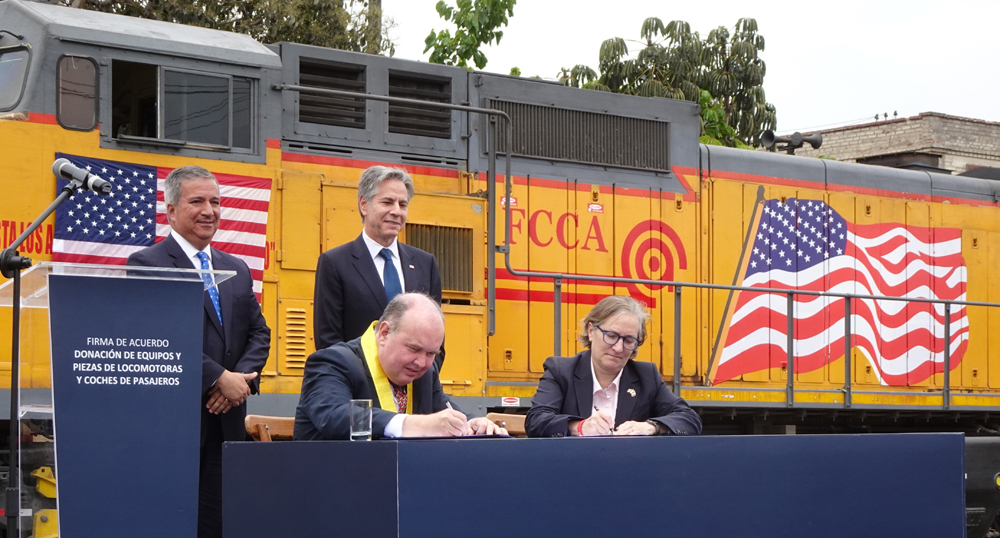 Four people in ceremony in front of former Union Pacific locomotive lettered for Peruvian rail operator FCCA