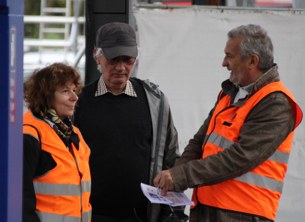 Man and woman in orange vests and second man in dark clothing