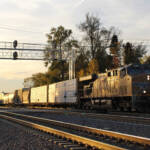 Train passing under signal bridge at sunset