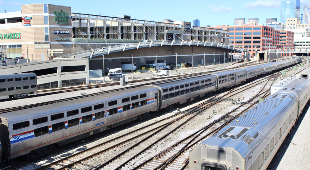 Passenger train moving away from camera through yard