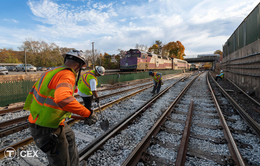 Men working on railroad tracks with commuter train in background