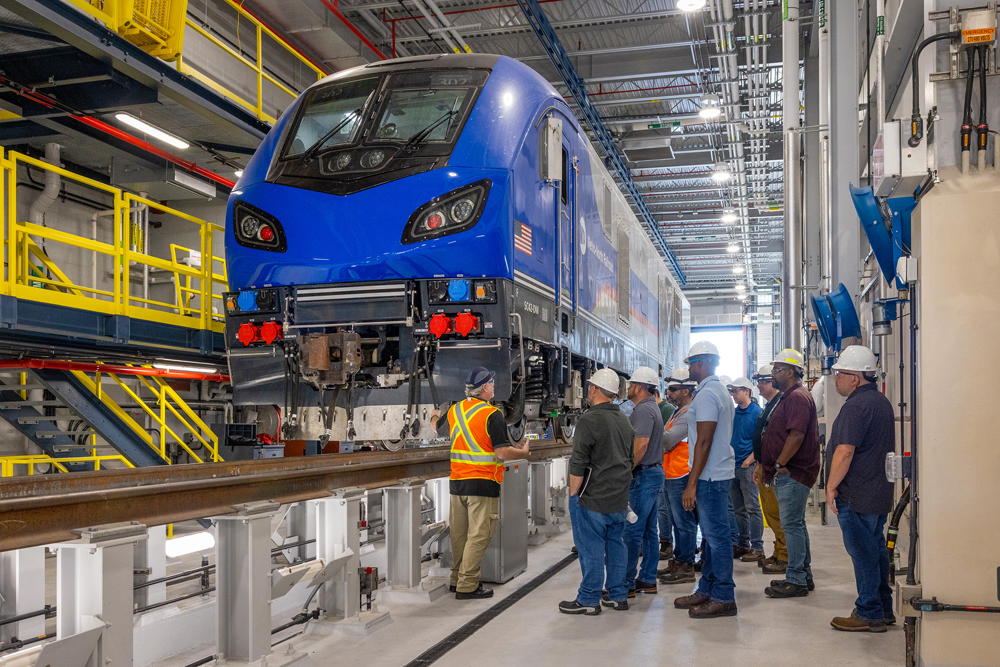 Maintenance workers looking at new locomotive in shop building