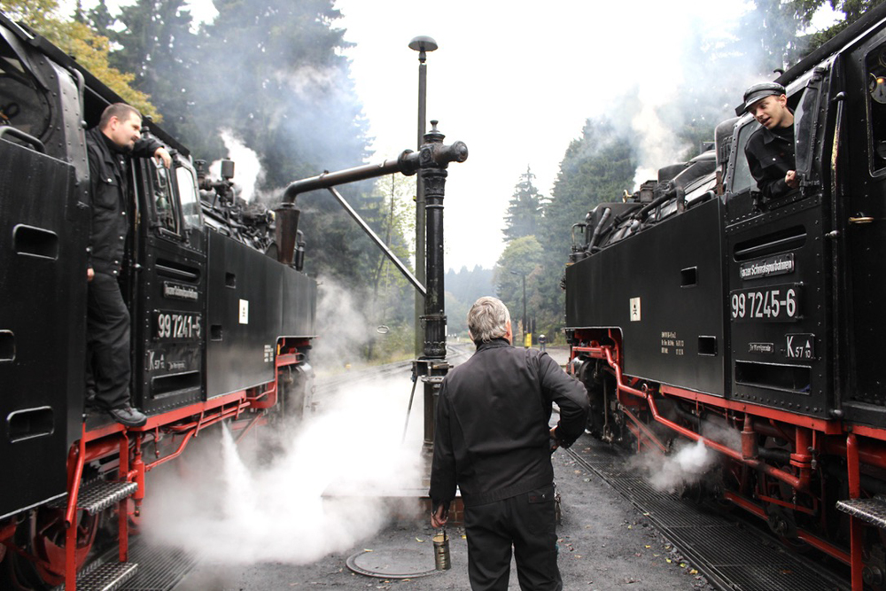 Locomotives side by side with crew members talking.