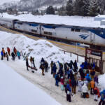 Passenger train in snow with people waiting to board