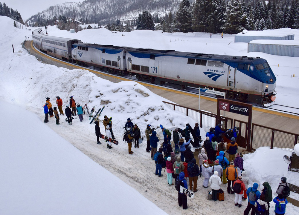 Passenger train in snow with people waiting to board