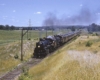 Two Grand Trunk Western steam locomotives on passenger train with people riding on tenders