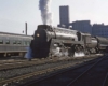 Streamlined smoking Grand Trunk Western steam locomotive with passenger train