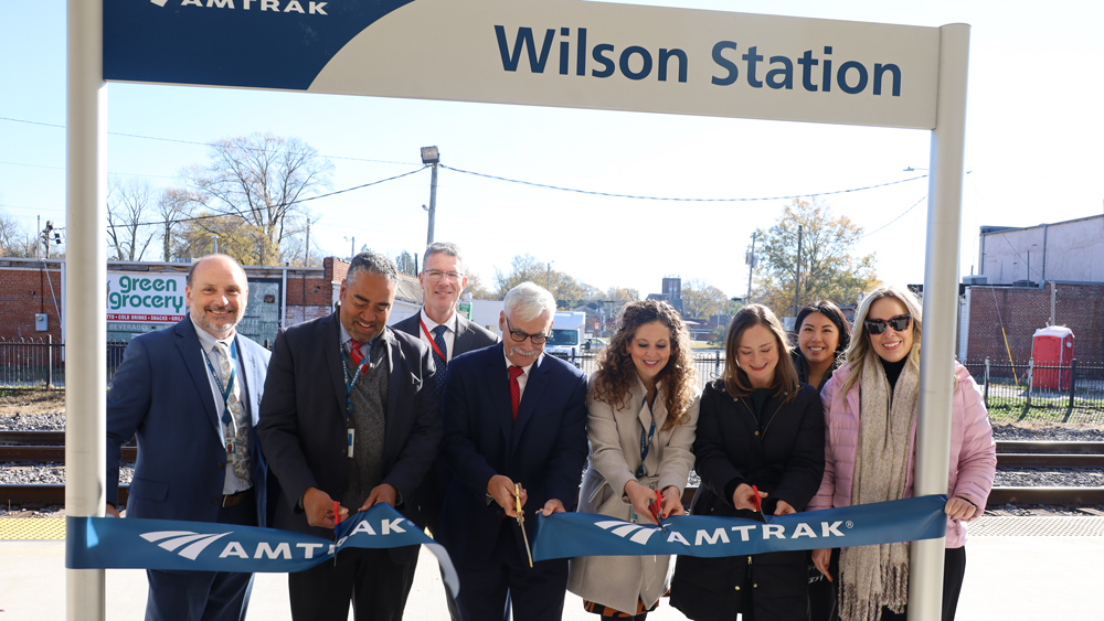 Ribbon-cutting ceremony in front of Amtrak station sign