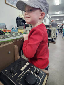 A little boy stands next to a train platform