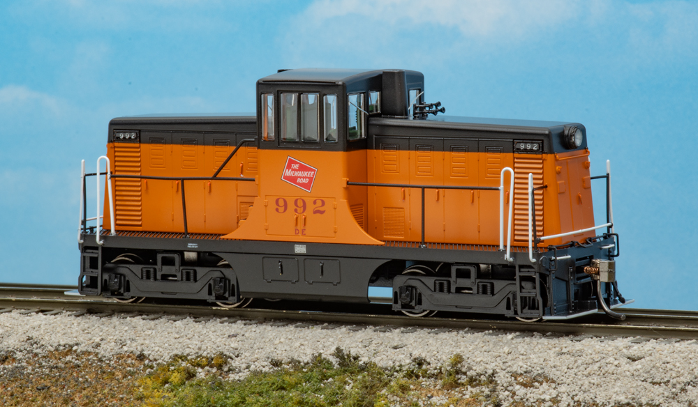 Color photo of HO scale center cab switcher painted orange and black on scenicked base. 