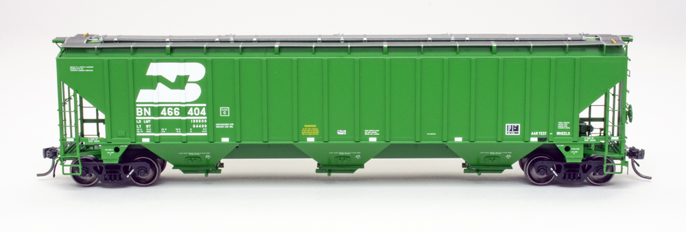 Side view of HO scale three-bay covered hopper painted green on white background.