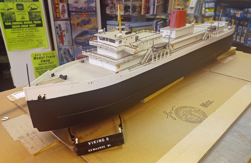 Color photo of N scale boat painted black and white on top of cardboard box.