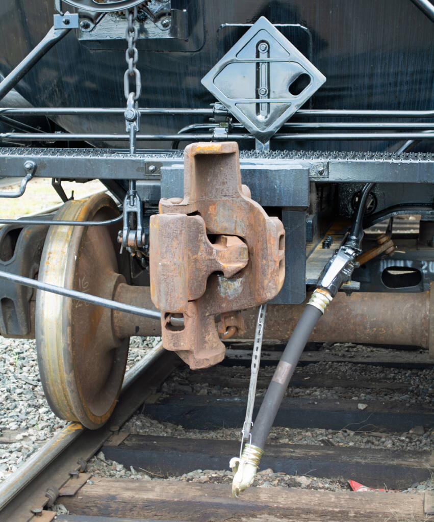 Color photo of rusty coupler on freshly painted black tank car.