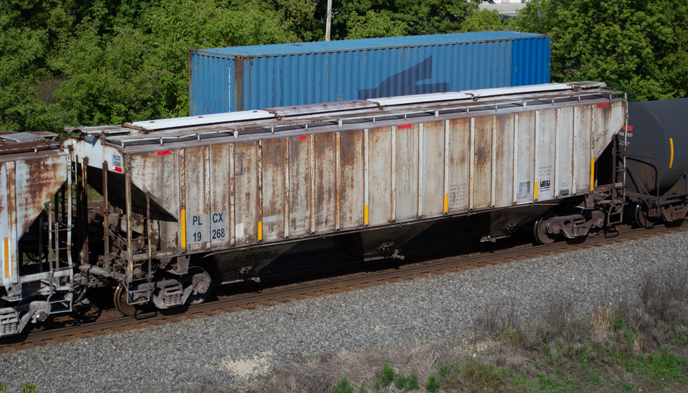 olor photo of a light gray covered hopper with rust and weathering.