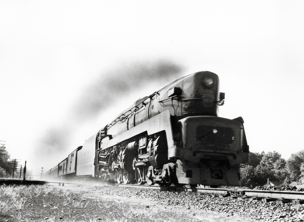 Black & white photo of a streamlined, high-speed steam locomotive pulling a passenger train. Pennsylvania Railroad T1 technology.